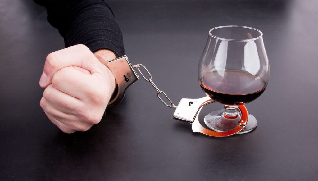 L'alcoolisme, la main dans les menottes et un verre de cognac
