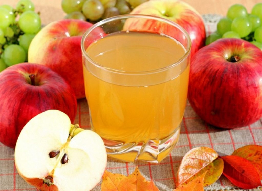 Obuolių sultys stiklinėje ir obuoliai